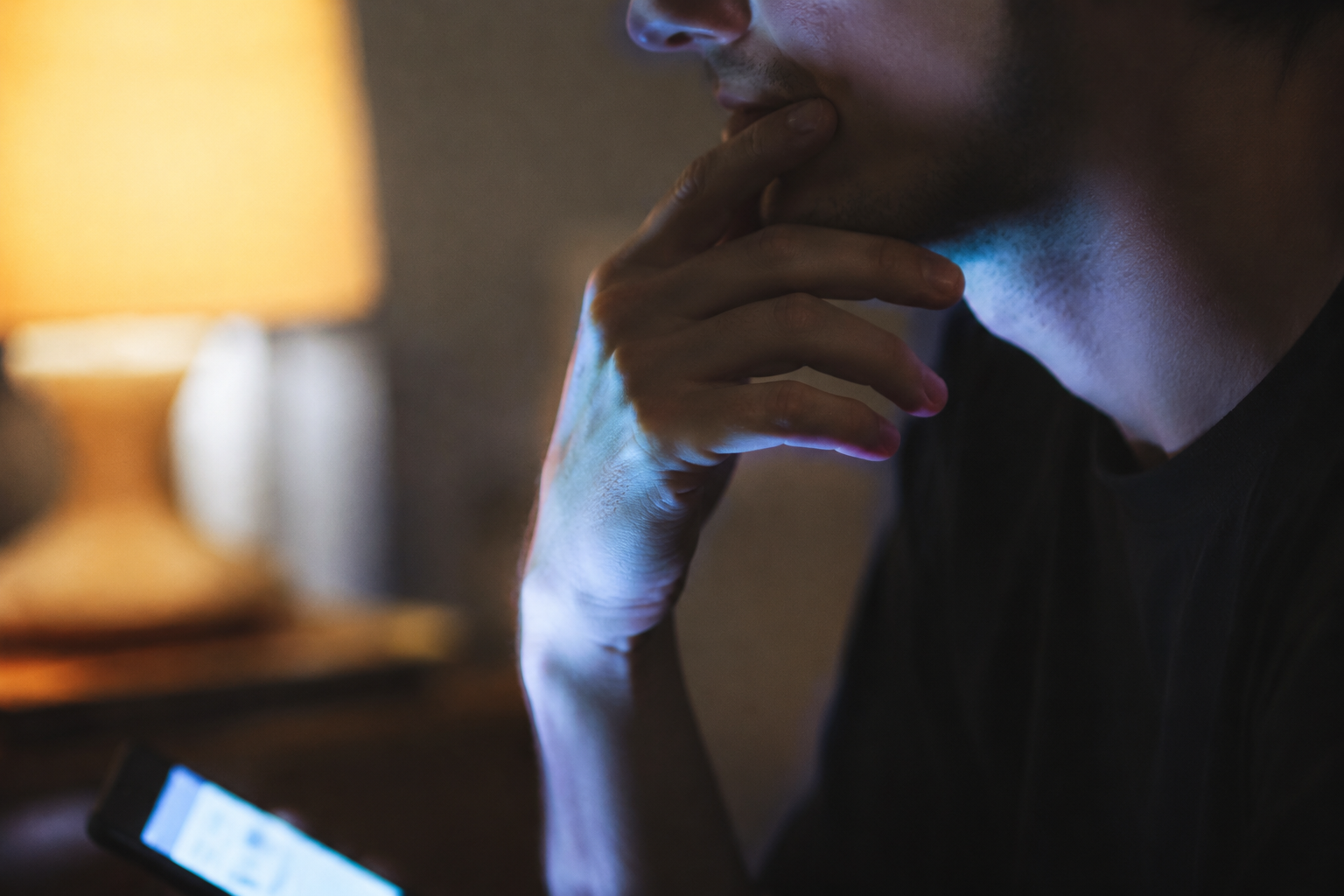 Person touching face while using smartphone, a common habit that spreads acne-causing bacteria to skin